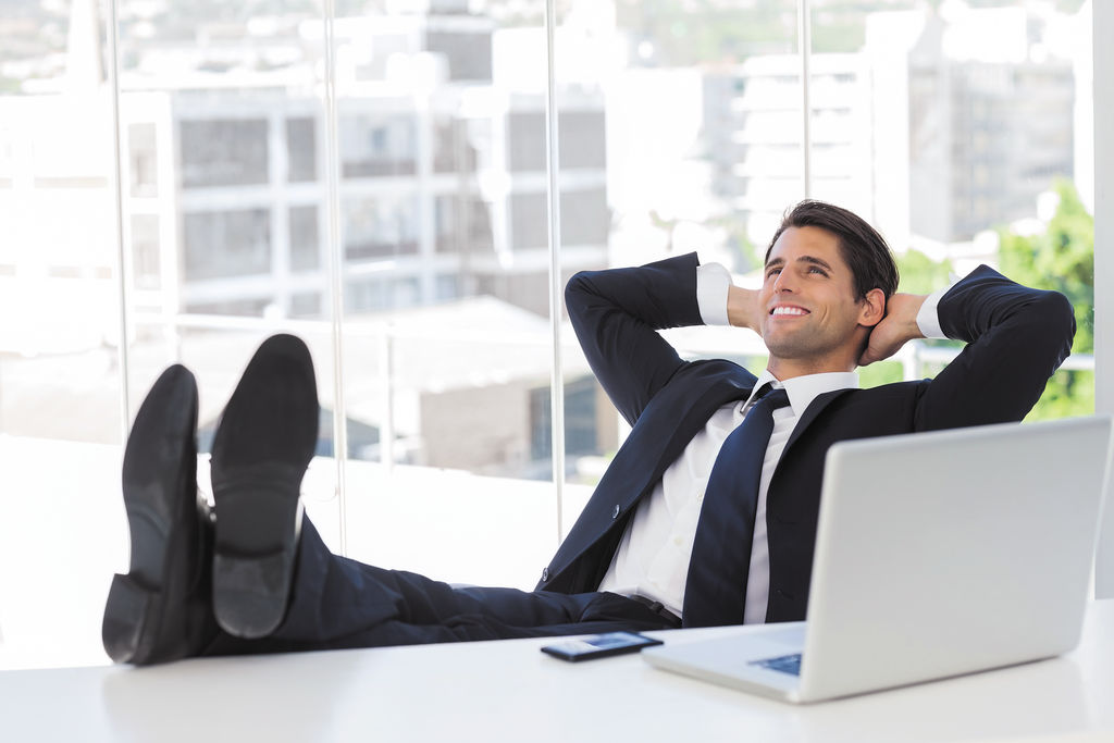 Successful businessman relaxing with his feet on his desk